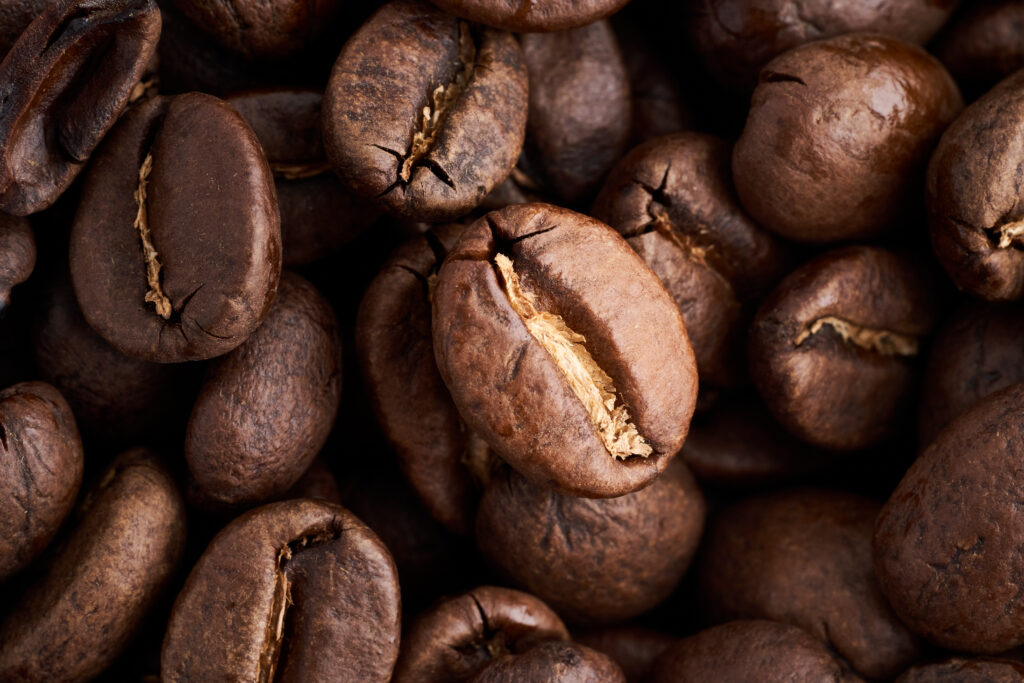 Macro of dark coffee arabica beans texture. Caffeine aroma. Pile of scented black grains